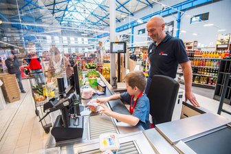 Kunden staunen nicht schlecht: An der Kasse im Auer Simmel-Markt sitzen Kinder - Kinder des Horts Auer Weltentdecker durften sich an die Kasse im Simmel Center Aue setzen, Kundin Elke Wuckel hatte überhaupt nichts dagegen, dass Luca Lenk sie abkassierte, Marktleiter Thomas Mittelstedt assistierte.
