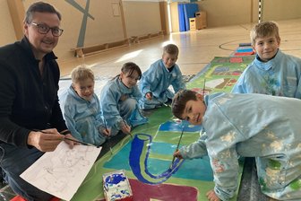 Kunst-Projekt in Oelsnitz: Kinder setzen sich für Kirchturmsanierung ein - André Wolf malt mit Jonas, Anni, Tim, Paul und Adrian während eines Kunstprojektes Plakate. Eines ist für die Kirchturm-Spendenaktion.