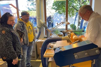 Kunsthandwerk trifft Tradition: Drechslerei Wagner in Hainichen wird zum Besuchermagneten - Katrin Krause (von links) und Guido Schneider schauen Volkmar Wagner beim Tag des traditionellen Handwerks in der Holzwerkstatt in Hainichen zu.