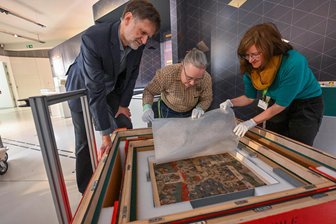 Kunsthistorische Sensation: Chemnitz zeigt lange verschollenes 500 Jahre altes Wimmelbild - Kurator Jens Beutmann, Restauratorin Gabriele Wagner und Věra Pinnoy aus Kutná Hora (von links) beim Auspacken des Bildes.