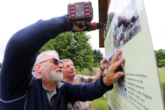 Kurz vor dem Jubiläum: Ärger über Vandalismus in Zug-Langenrinne - Gerd Bellmann (l.) und Hubert Göhler befestigen die Tafel zum Bahnhof Langenrinne.
