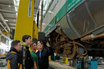 Länderbahn in Neumark bietet erstmals Einblicke bei Aktion "Schau rein!" - Schüler der Klasse 9a der Oberschule Neumark lassen sich von den Lehrlingen Lucian Trömel (3. v. l.) und Dominik Ehlert (r.) in der Werkstatt in Neumark das Fahrwerk eines Regio-Shuttles erklären.