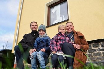 Lagerfeuer, Leckereien, Lieder: Oelsnitzer Adventskalender wird lebendig - Susanne und Matthias Huster mit ihren Kindern Jonathan und Johanna machen den Anfang beim Lebendigen Adventskalender in Oelsnitz. Dafür haben sie die Zahl 1 an ihr Fenster angebracht.