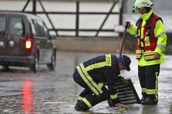 Land unter in St. Egidien und Lobsdorf - Feuerwehrleute heben die Gullydeckel aus der Fahrbahn. Die Siebe der Einläufe waren mit Schlamm und Dreck zugesetzt, sodass die Gullys die Wassermassen nicht mehr schlucken konnten.