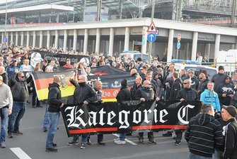 Landkreis Zwickau verbietet Konzert von Neonazis - Bei einer Hooligan-Demo in Köln von 2014 tragen Teilnehmer ein Transparent mit dem Namen der rechten Band vor sich her. Die Polizei bezeichnet mit dem Begriff gewaltbereite Fans.