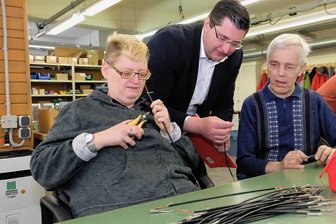 Lebenshilfe Reichenbach: 2024 soll der Bau der neuen Werkstatt starten - Bei einem Rundgang durch die Werkstatt schaut Landrat Thomas Hennig (Mitte) Daniel Conrad (l.) und Ralf Friedel bei der Kabelkonfektionierung für eine Elsterberger Firma über die Schulter. 