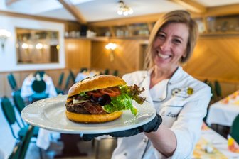 Leckerster Burger im Erzgebirge gesucht: In Leukersdorf kommt Fleisch vom Biohof auf den Tisch - In der Sportgaststätte Leukersdorf stehen neben vielen anderen Gerichten auch Burger auf der Speisekarte. Die Gaststätten-Chefin Claudia Lappöhn präsentiert einen davon.