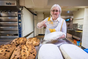 Leckerster Stollen im Erzgebirge gesucht: Bäckerei in Carlsfeld bleibt traditionell - Kerstin Schönfelder zuckert einen der Stollen aus der Bäckerei in Carlsfeld.
