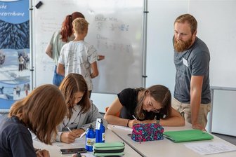 Lernen und Lehren in den Ferien: Wo Lehrer im Vogtland auf Urlaub verzichten - In die Welt von Watt, Volt und Ampere lässt Physiklehrer Frederick Börner (rechts) die College-Neuntklässlerinnen Linda Schimmack, Chantal und Xenia Dolle (von rechts) eintauchen. Hinten an der Tafel: Elftklässlerin Kimberly Fehlkamm gibt Fynn Mathe-Nachhilfe. 