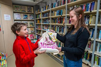 Leseabenteuer aus dem Bus: Bücherbeutel für Mittelsachsens Kinder - Malte Knorr freut sich über den Lesebeutel, dem ihm Anne Rombach überreicht.
