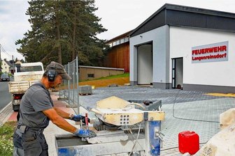 Letzte Handgriffe an neuer Fahrzeughalle der Ortswehr in Langenreinsdorf - Heiko Hölzel von der Langenreinsdorfer Firma SWT schneidet Pflastersteine für die Außenanlagen des neuen Feuerwehrgerätehauses in dem Crimmitschauer Ortsteil zurecht. 