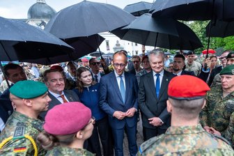 Litauen: Fest-Appell für Bundeswehr-Brigade - Bundeskanzler Friedrich Merz (CDU, Mitte) steht neben Gitanas Nauseda (Mitte, rechts), Präsident von Litauen, Boris Pistorius (SPD, 2. von links), Verteidigungsminister, sowie Dovile Sakaliene, Verteidigungsministerin von Litauen – umringt von Bundeswehrsoldaten der Panzerbrigade 45.