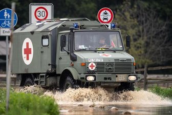 Ein Sanitätsfahrzeug der Bundeswehr fährt über eine überflutete Straße.
