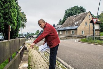 Lkw-Ärger im Erzgebirge: Bei Herrn Gottfried gab es schon fünf Unfälle - Christoph Gottfried zeigt die Mauer, von der mehrere Meter weggerissen wurden. Auch eine Straßenlaterne (hinten) wurde bei einem der Vorfälle von einem Lkw in Mitleidenschaft gezogen. 