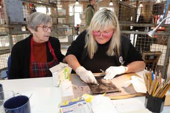Lößnitzer Makers mit pfiffigen Ideen: Wo aus Schrott plötzlich Kunst wird - Barbara Zimmermann (l.) aus Chemnitz gab ihr Wissen rund um Radierungen mit Tetrapack weiter. Rosi Eisermann probierte es aus.