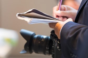 Lokaljournalismus unter Druck: „Freie Presse“ diskutiert in Freiberg mit - Ein Journalist macht sich Notizen. Dazu hat er eine Kamera dabei.