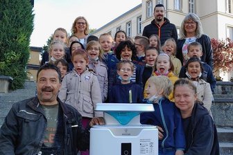 Luftfilter für Schulen: Reichenbacher Eltern zeigen, wie's geht - Handeln statt reden. Die Eltern von Erstklässler Cedric (vorn mit Mutter Nadine/links Vater Mike Döbereiner) haben der Weinhold-Grundschule einen Luftfilter geschenkt. Hinten links Schulleiterin Simone Wünsch, rechts Klassenlehrerin Sabine Böhm. Daneben Sebastian Müller von Hifi-Böhm, der sich um die neue Technik kümmert.