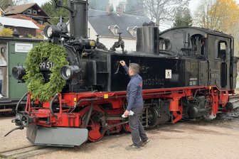 „Mach’s gut, alte Dame!“ – Hunderte begleiten Dampflok 99 516 im Erzgebirge auf letzter Fahrt - Der Vereinsvorsitzende der Museumsbahn Schönheide, Anton Weigel, bringt mit Kreide an der Lok die Aufschrift mit ihrem letzten Einsatztag an.