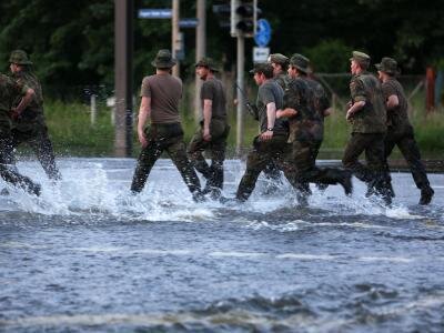Magdeburg kämpft - Höhere Flut als erwartet - Bundeswehrsoldaten rennen im Ortsteil Rothensee in Magdeburg über eine überflutete Straße.