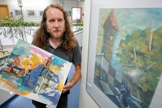 Malerischer Blick auf Auerbach - Mario Schmidt mit dem Bild "Im wunderlich wilden Wandel der Zeit" in der Hand. Das rechte Bild heiß "Das altbekannte Spiel".
