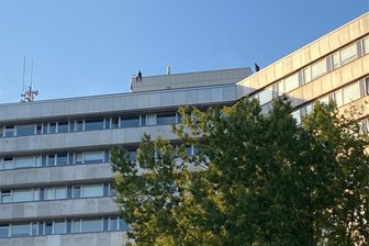 Mann auf Dach von „Parteisäge“ sorgt für Aufsehen - Während unten hunderte Menschen demonstrierten, schaute ein Mann vom Dach der „Parteisäge“ auf das Geschehen herab.