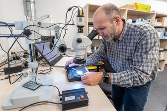 Marienberger Polizei stockt auf: Was hat der neue Anbau am Revier zu bieten? - Kriminaltechniker Rico Oelmann schaut sich im kriminaltechnischen Untersuchungsraum des neuen Anbaus Lackpartikel eines Pkw unter einem Mikroskop an.