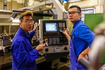 Maschinenbauer setzt auf Azubis aus Vietnam: Wie Anh und Cong Sachsen wurden - „Fräsen, Drehen, Schleifen. Wir haben was zu tun.“ Die angehenden Zerspanungsmechaniker Quang Anh Dao (l.) und Cao Cong Kieu an einer CNC-Drehmaschine bei SLF.