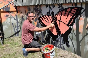 Mauer am Kreisel wird zum Hingucker - André Wolf aus Kürbitz hat die Stützmauer zum Bahndamm hin im Freizeitgelände am Kreisverkehr in Lengenfeld mit Schmetterlingen und Blumen besprüht.