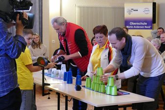 MDR-Moderator wird in Zschopau zum Becherstapler - Unter Anleitung von Lehrerin Fanija Büchner versuchten sich Moderator Mario D. Richardt (vorn) und Zschopaus Oberbürgermeister Arne Sigmund im Speedstacking.
