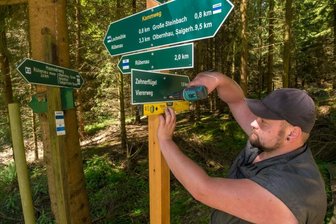 Mega-Projekt: Neue Schilder für 330 Kilometer langes Wegenetz - Peter Wießner, Vorarbeiter bei dem bauausführenden Unternehmen aus Lichtenberg, montiert an der Kreuzung von Hammerweg und A-Flügel die Beschilderung an einen neu gesetzten Pfahl - ein Bestandteil des 330 Kilometer langen Wanderwegenetzes, das die Stadt Olbernhau in Ordnung bringen lässt.