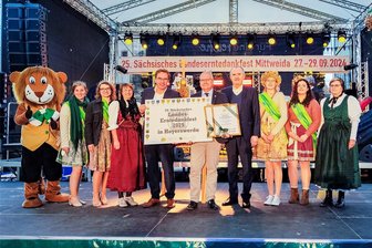 Mehr Darsteller beim Festumzug, kaum Kriminalität: 35.000 Besucher kamen zum Landeserntedankfest nach Mittweida - Staatsminister Thomas Schmidt (4. v. r.) und Stadtchef Schreiber (5. v. l.) überreichten Hoyerswerdas Oberbürgermeister Torsten Ruban-Zeh (4. v. r.) die Ausrichterurkunde für das Landeserntedankfest 2025.
