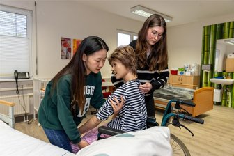 Mehr Stellen als Bewerber: Jugendliche im Vogtland profitieren vom Fachkräftemangel - Die Auszubildenden Trang Nguyen und Annelie Schramm (v. l.) üben im Pflegekabinett der Awo in Auerbach das fachgerechte Mobilisieren von hilfsbedürftigen Menschen. Um Fachkräfte zu gewinnen, werden diese seit geraumer Zeit aus Asien rekrutiert.