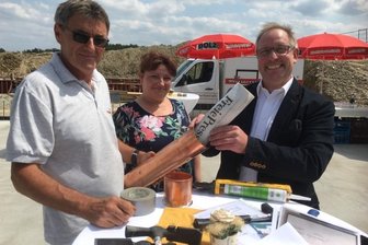 Metzgerei Dölz legt Grundstein für Hofladen - Ein Zeugnis für die Nachwelt: Polier Frank Brenner (links) sowie Mandy und Heiko Dölz haben bei der Grundsteinlegung unter anderem eine aktuelle Ausgabe der "Freien Presse" in die Kartusche gesteckt.