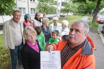 Mieter in Angst: Trinkwasser-Sperre droht - Marita und Steffen Wünsch (vorn) und andere Mieter der Häuser Carl-von-Ossietzky-Straße 107, 109 und 111 mit dem Aushang, in dem ihnen der Versorger Eins die Einstellung der Trinkwasserlieferung und das Abschalten des Stroms für das Hauslicht für kommenden Montag ankündigt.