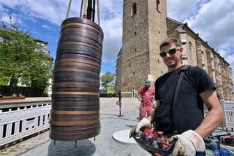 Millimeterarbeit an XL-Münzstapel im Erzgebirge: Dieses Kunstwerk ist ein schwerer Brocken - Exakt musste der Kranführer Robert Dehmel in Schneeberg den Münzstapel auf die vier Bohrungen des Fundaments setzen.