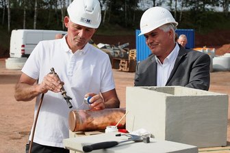 Millionen-Investition in Wildenfels: An der A 72 entsteht ein Logistikzentrum - Bauleiter Ralf Tschentscher (links) verschließt die mit Zeitdokumenten gefüllte Hülse, ehe er diese gemeinsam mit dem Wildenfelser Bürgermeister Tino Kögler in den Grundstein versenkt. 