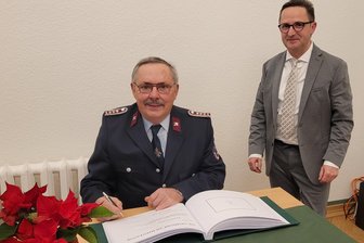Mit 70 Jahren noch aktiver Feuerwehrmann: Wie macht Thomas Oelsner aus Lichtentanne das? - Im Beisein von Bürgermeister Tino Obst trägt sich Thomas Oelsner ins Ehrenbuch ein.