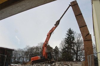 Mit Abriss des alten Schornsteins in Coschütz geht eine Odyssee zu Ende - Ein verlängerter Baggerarm, an dessen Ende ein Greifer befestigt ist, reißt den Schornstein ein.