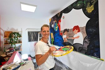 Mit bunter Farbe und viel Weltraum: Wie die Bibliothek in Neukirchen zukunftsfähig werden möchte - Das neue Wandbild in der Bibliothek Neukirchen hat Sylvia Köhler innerhalb von vier Tagen gemalt. Die Idee dazu arbeitete sie gemeinsam mit Bibliotheksleiterin Heidi Eismann aus.