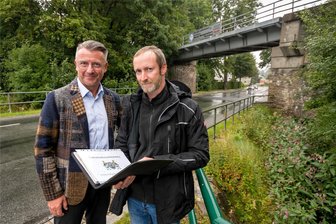 Mit dem Fahrrad Richtung Tschechien: Radweg auf stillgelegter Bahntrasse im Erzgebirge überraschend genehmigt - Marienbergs Oberbürgermeister André Heinrich und der Projektverantwortliche Sebastian Baldauf (v. l.) schauen sich die ehemalige Bahnbrücke über die Reitzenhainer Straße an. Mit Beginn des Radwegbaus soll sie von der Bildfläche verschwinden.