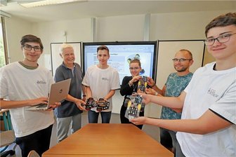 Mit Mini-Roboter aufs Siegertreppchen: Gymnasiasten aus Freiberg ertüfteln sich Platz bei World Robot Olympiad - Logan (l.), Finnian (r.), Eva und Maximilian zeigen gemeinsam mit Kursleiter Olaf Schulze (2.v.l.) und Mathelehrer Roy Sommer (2.v.r.) die Ergebnisse ihrer Arbeit.