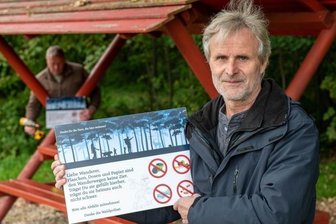 Mit Schildern gegen den Müll - Der Seelitzer Bürgermeister Thomas Oertel zeigt eines der Schilder gegen Müllablagerung, die die Gemeinde an Sitzgelegenheiten der Wanderwege anbringen ließ - wie hier zwischen Biesern und Steudten. 