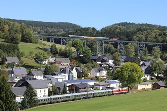Mit Volldampf durchs Erzgebirge: Sonderzüge zum Tag der Schiene locken Hunderte Eisenbahnfans an - Nach dem Bahnhof Markersbach müssen Züge Richtung Scheibenberg eine starke Steigung bewältigen. Der Zug auf dem Viadukt fährt Richtung Schwarzenberg, der Gegenzug wartet im Bahnhof.