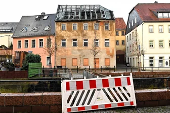 Mitten in der Stadt: Häuserteile stürzen in Hainichen auf Fußweg und Straße - Von diesem Haus am Übergang der Marktstraße zur Straße Am Damm in Hainichen sind Teile abgestürzt. Der Bereich davor ist komplett abgesperrt worden. Auch die Fußgängerbrücke, die von der Spülgasse hinüberführt, wurde abgeriegelt.