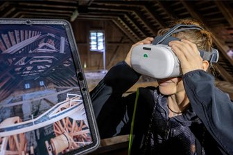 Montanregion Erzgebirge virtuell: Wasserräder drehen sich nach 150 Jahren wieder - Dorothea Doerffel vom Verein IV. Lichtloch des Rothschönberger Stollns präsentiert die Brille, mit der eine Illusion der historischen Wasserräder geschaffen wird. Auf dem Bildschirm ist zu sehen, was auch die Brille anzeigt.