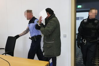 Mord oder Totschlag? Mann nach Tötung seiner Ehefrau in Chemnitz vor Gericht - Der Angeklagte wurde in Handschellen in den Sitzungssaal geführt.
