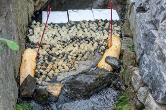 Motoröl in Bach im Erzgebirge: Einsatzkräfte nähern sich der Ursache - Mit Sperren soll die weitere Ausbreitung des Motoröls im Wasser verhindert werden.