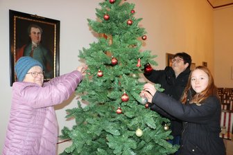 Mühltroffer Rauschebart zündet die Lichter am Baum an - Karin Lenk, Heike Graap und Lilli Zeuner (von links) schmücken den Baum im Kospoth-Saal.