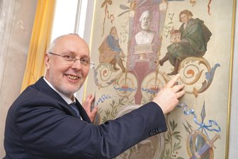 Musenhof Schloss Wildenfels: Ein Graf hat den Grundstein gelegt - Gerd-Helge Vogel vor einem Wandbild auf Schloss Wildenfels.