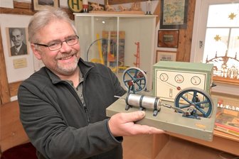 Museum im Erzgebirge zeigt zu Weihnachten „Spielzeug mit Strom“ - In der Ausstellung im Museum Schönheide gibt es Spielzeug mit Strom zu entdecken. Dazu gehört der elektromagnetische Motor, den Museumsleiter Andreas Schubert aus der Vitrine geholt hat.